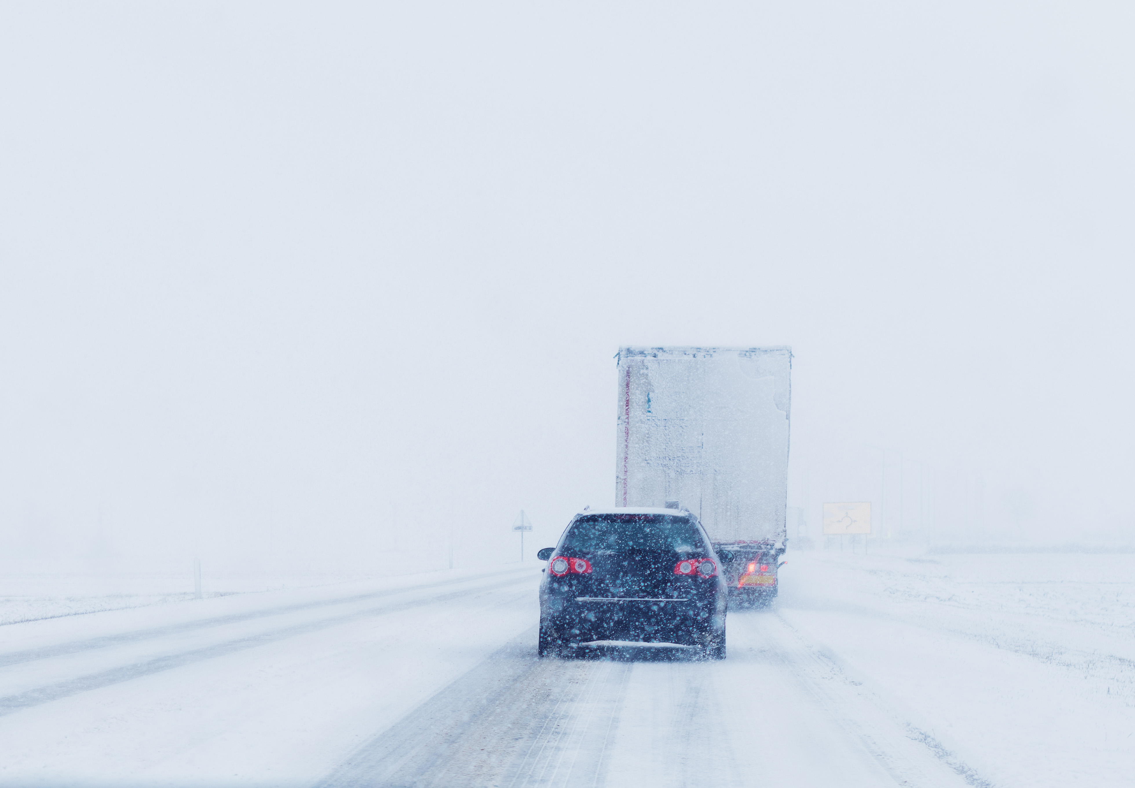 Vehicles driving on a snowy road in poor visibility conditions