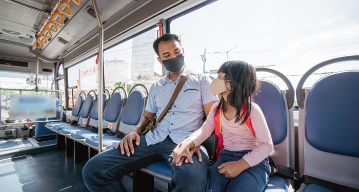 Adult and child wearing medical masks on public transit