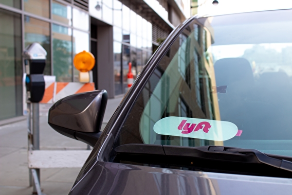 Car parked at a curb with a Lyft sign in the window