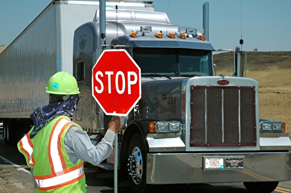 Work-zone flagger holding up a stop sign to a semi truck