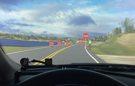 View from the dashboard of the simulator, showing a work-zone flagger standing at a roadside
