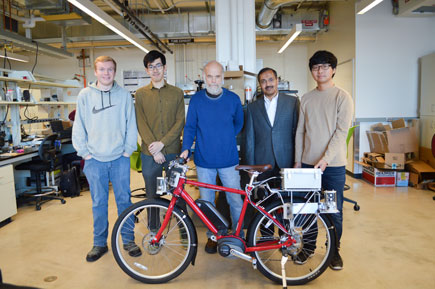 Researcher Rajesh Rajamani and four male members of research team standing behind red bike in lab