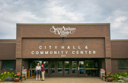 Two people standing in front of Saint Anthony Village City Hall and Community Center
