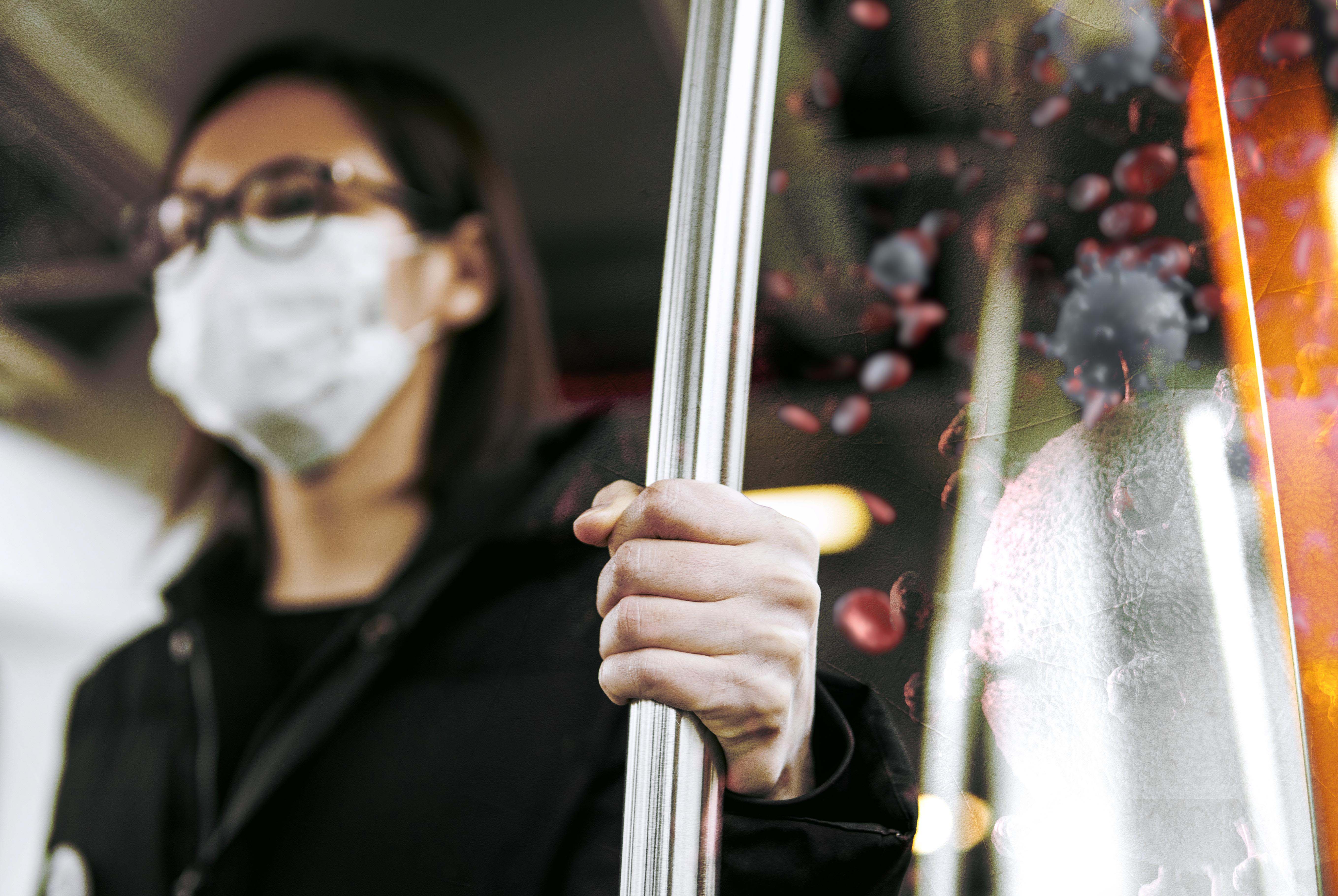 masked woman holding bus pole