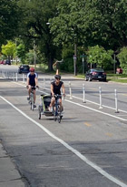 Two people riding bikes in a separated bike lane on a neighborhood street