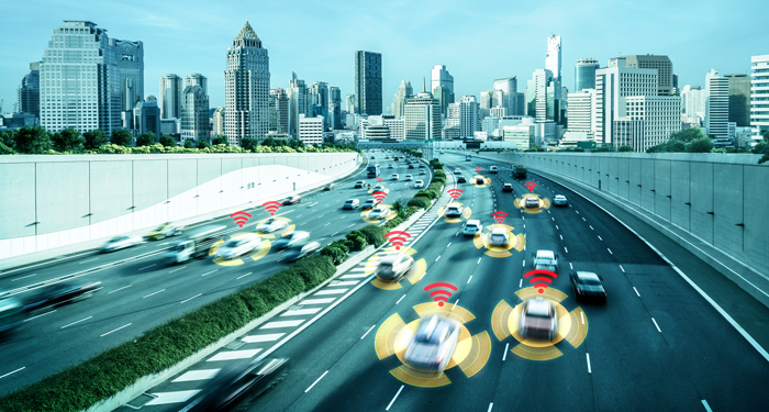 Connected vehicles on a freeway with a city skyline in the background