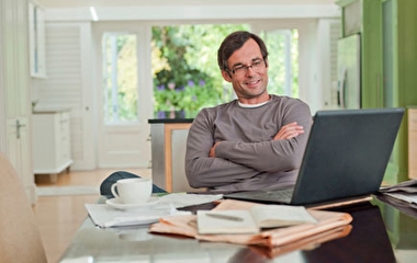 Man sitting at a table with a laptop in his home