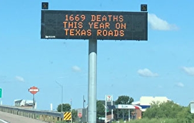 A roadside electronic messaging sign reading "1669 deaths this year on Texas roads"