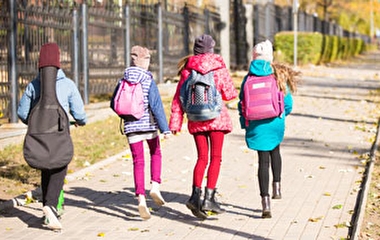 A group of children walking to school on a sidewalk