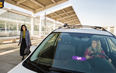 Woman walking toward a vehicle with a Lyft sign in the window