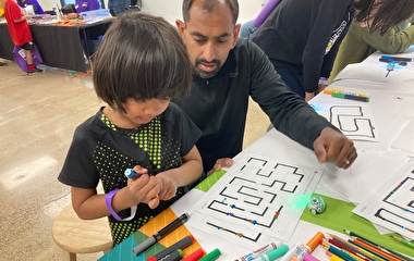 A child and their parent experimenting with Ozobots at Tech Fest