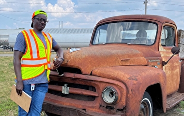 MnDOT intern leaning against an old truck