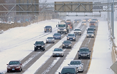 Traffic driving on a freeway partially covered with snow