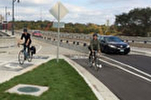 Bicylicsts riding in dedicated bike lanes with vehicle traffic in the background