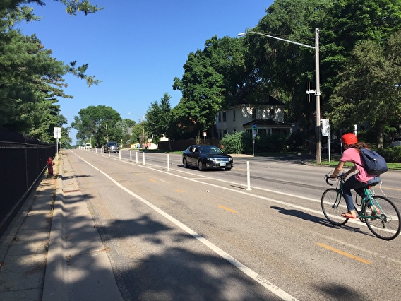 Person with a backpack biking in a separated bike lane