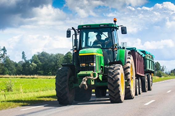 Tractor driving on a paved roadway