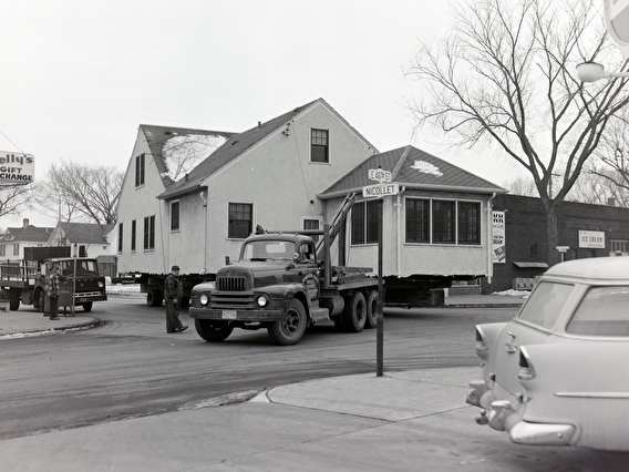 A house being moved out of a Minneapolis neighborhood on a trailer