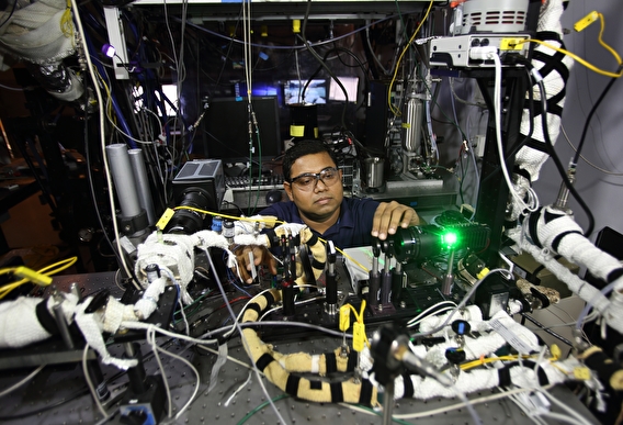 Sayan Biswas crouching in front of a table covered in equipment.