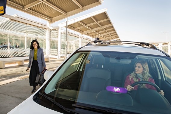 Woman walking toward a vehicle with a Lyft sign in the window