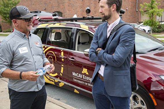 Phil Magney and Kyle Shelton talking in front of the MnCAV Ecosystem vehicle