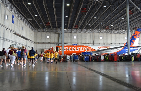 Students in a hangar walking toward a Sun Country aircraft