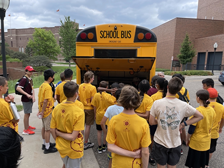 Students gathered around the back of an electric school bus