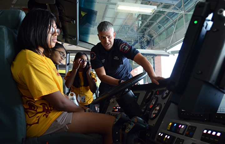 Three campers getting a view inside a Fire and Rescue vehicle at MSP Airport