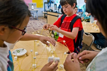Three kids at White Earth summer camp building bridges with spaghetti and marshmallows