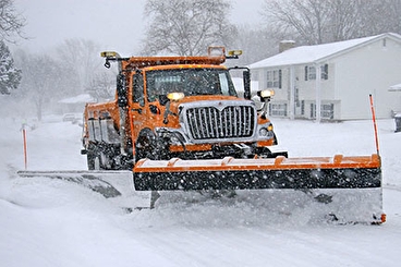 Snow plow in front of houses