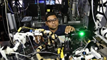 Sayan Biswas crouching in front of a table covered in equipment.